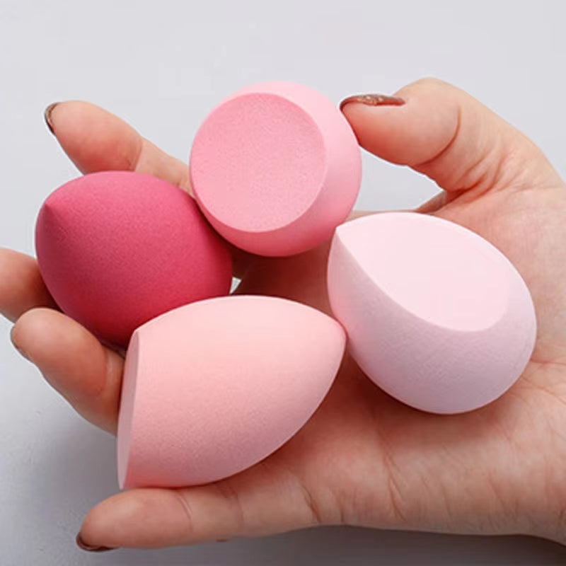 Teardrop makeup sponges in pink and rose tones, held in hand