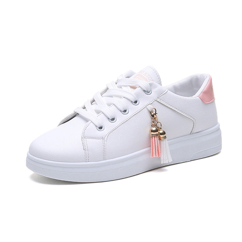 White low-top sneakers with pink collar trim and tassel charm, lace-up.