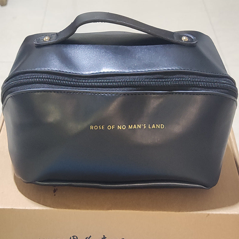 Dark blue cosmetic bag with top handle and front zipper, logo centered on front