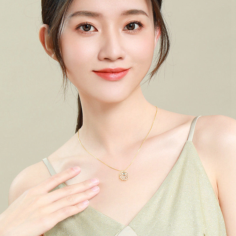 Four-leaf clover pendant necklace on thin gold-tone chain, small sparkle charm