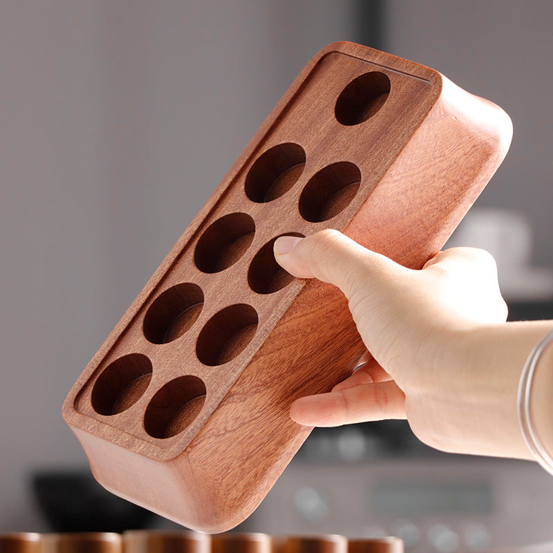 Wooden display tray with circular holes, with a hand placing a glass tube