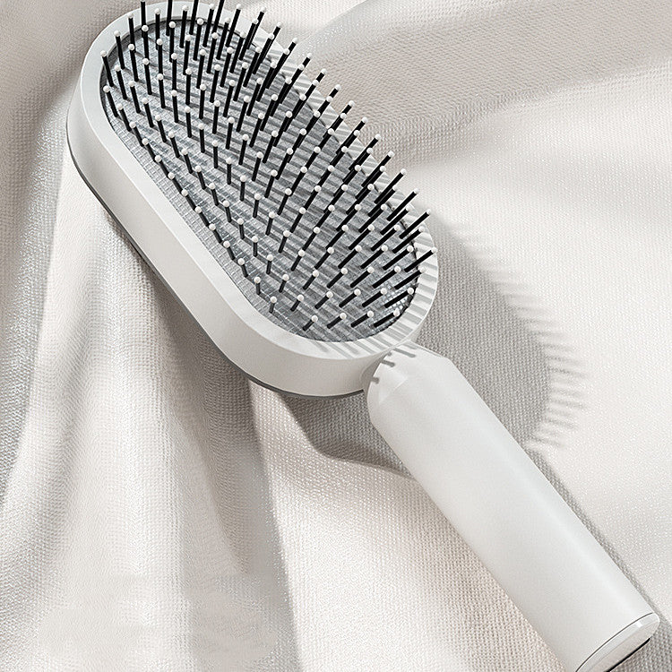 Self-cleaning hair brush with dense black pin bristles on a white oval head