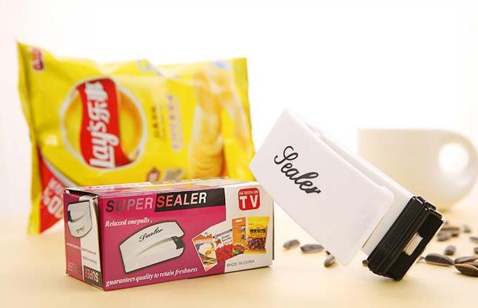White heat sealer next to a packaged food pouch, with black sealing clamp
