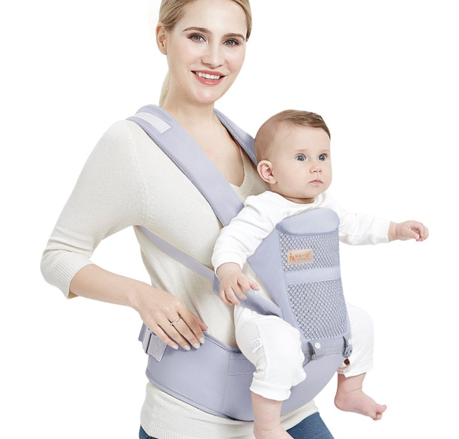 Light gray baby waist carrier and stool worn by parent holding a baby