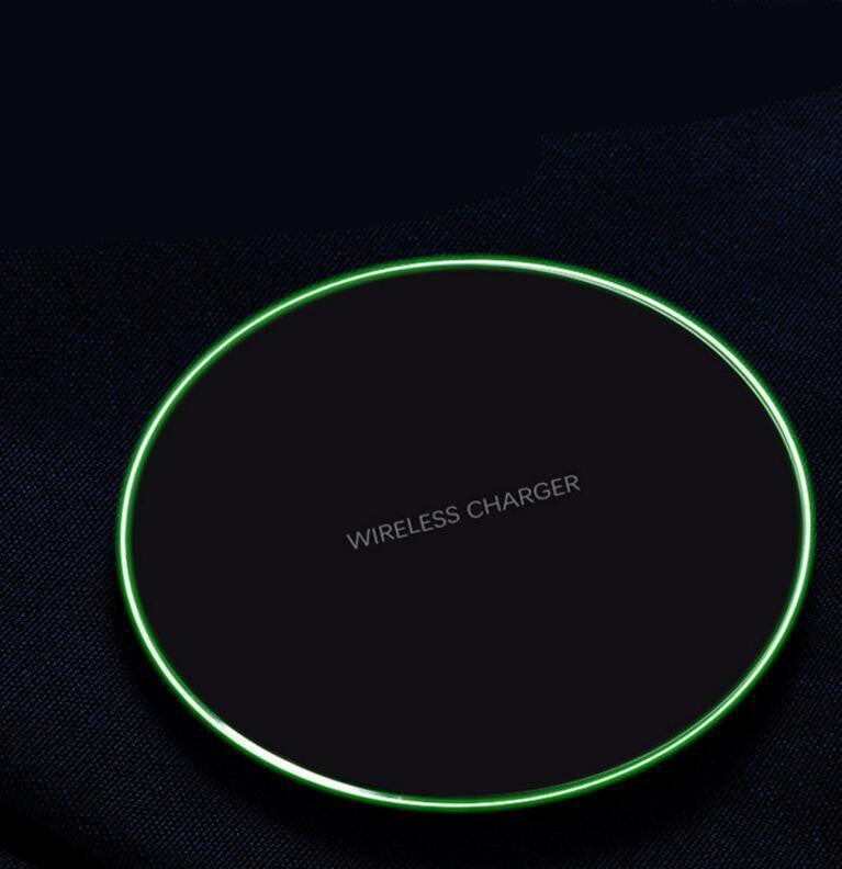 Black wireless charger pad with glowing green LED ring on dark fabric