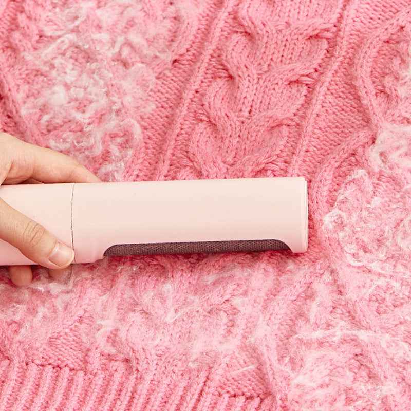 Pet hair remover lint roller brush with rectangular dark cleaning pad on knit sweater