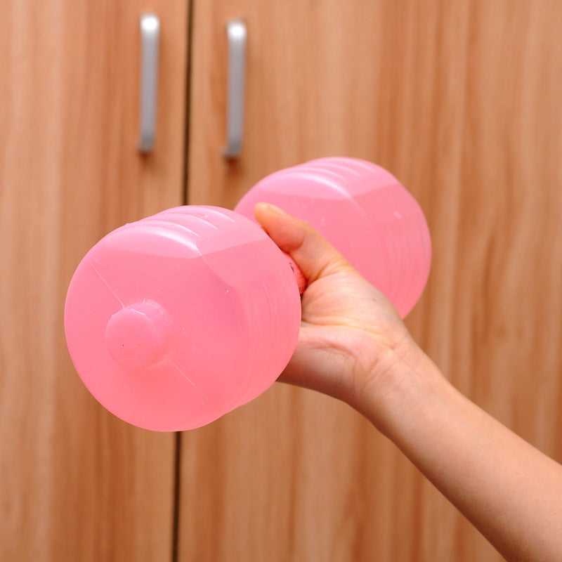 Pink water dumbbells held in hand against wooden background