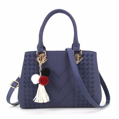 Royal blue quilt-textured handbag with top handles, crossbody strap, and pom tassel charm