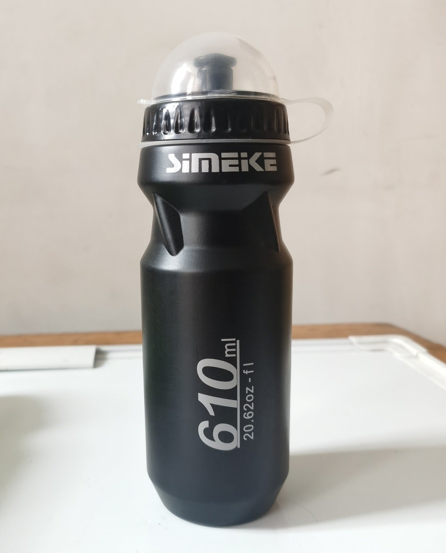 Black bicycle water bottle, 610 ml, with flip top and carrying loop.