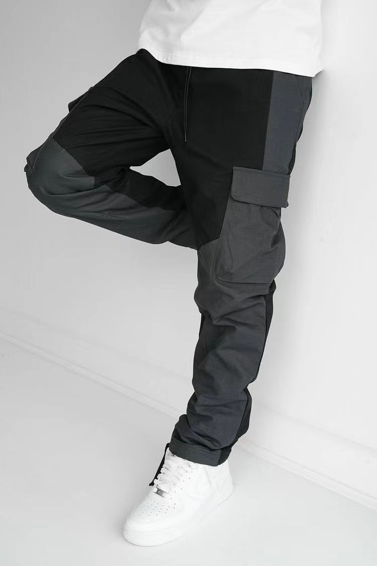 Black cargo trousers with stitched pocket panels and thigh flap, loose cuffed hem