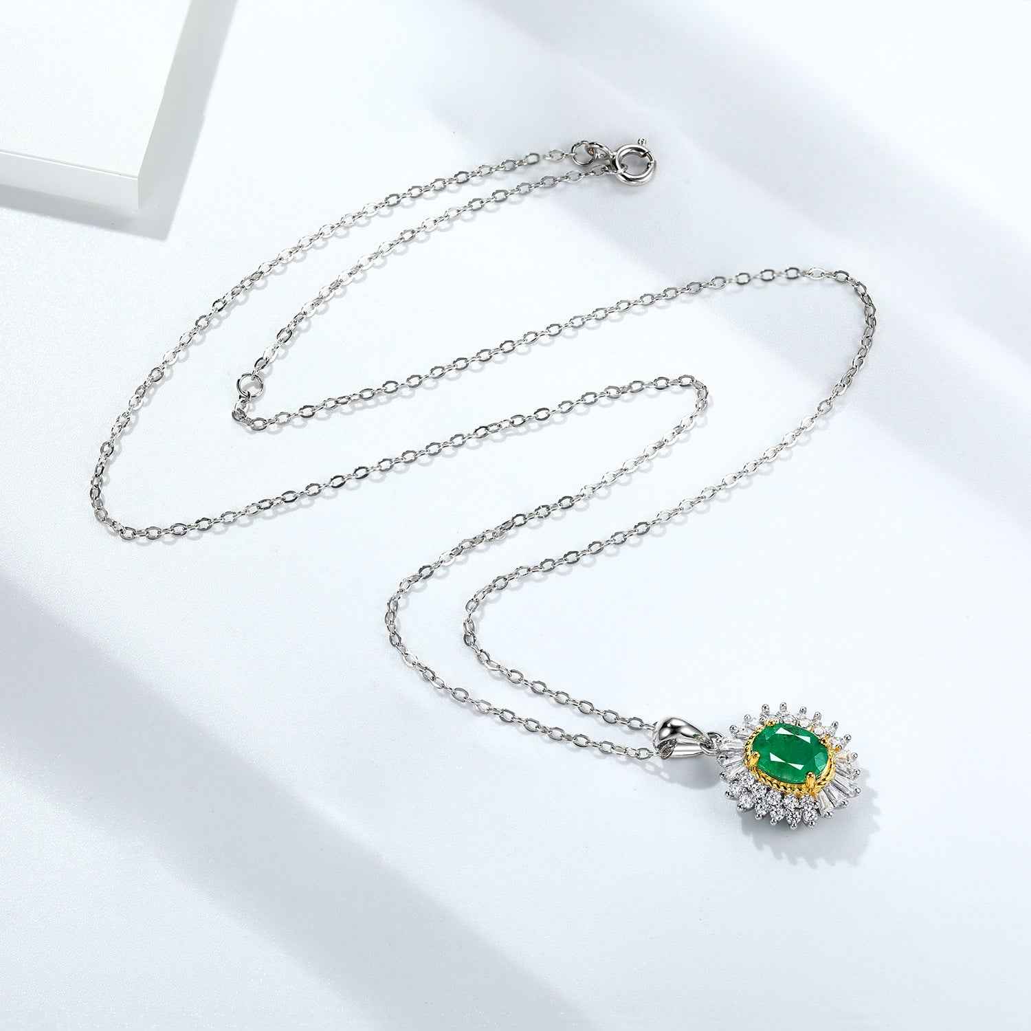 Oval green gemstone pendant necklace on silver chain with crystal halo and gold bezel