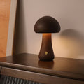 Dark wooden mushroom LED night light on a cabinet shelf, glowing warm light