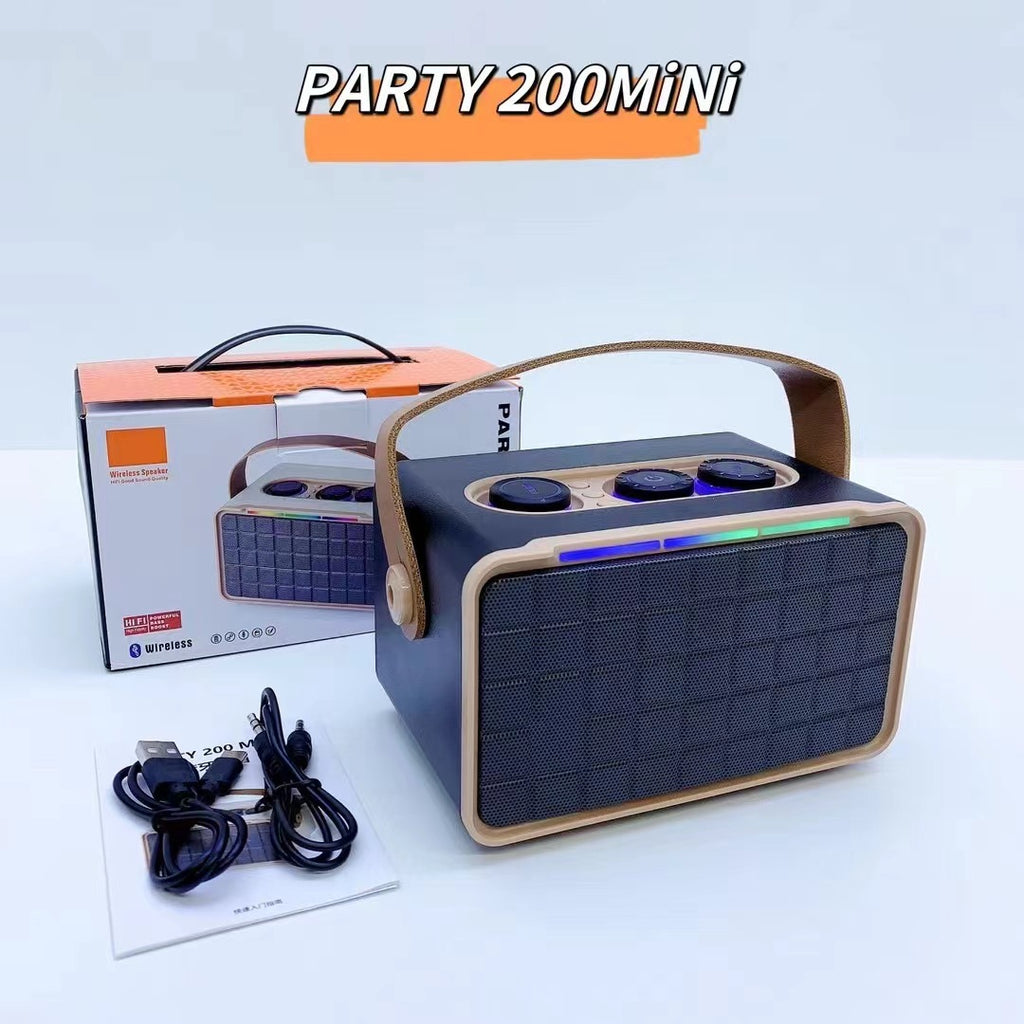 Khaki outdoor Bluetooth speaker with RGB bar and dark grille, cables and box behind