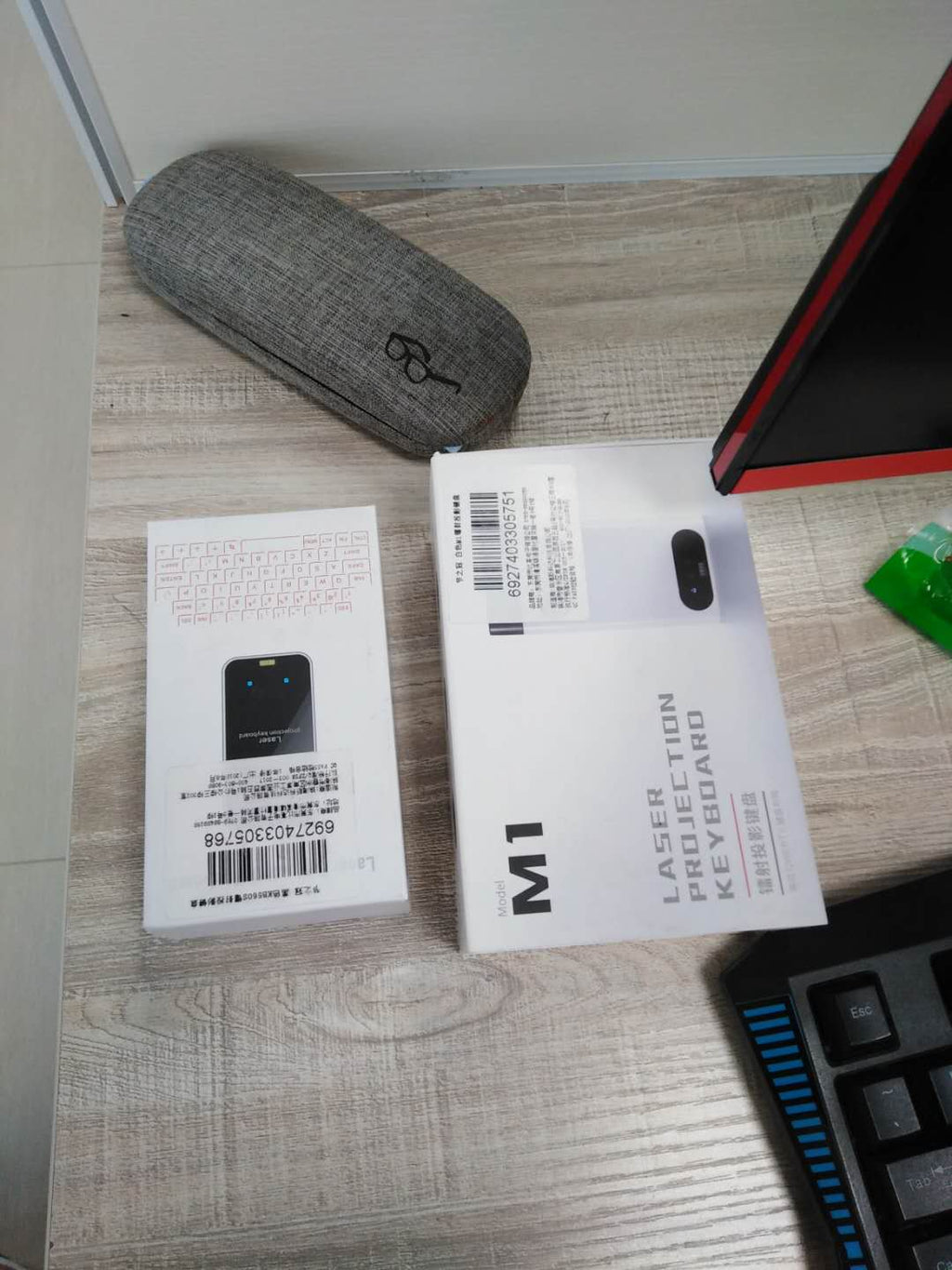 Laser projection keyboard projector and mouse accessory with product packaging on a tabletop