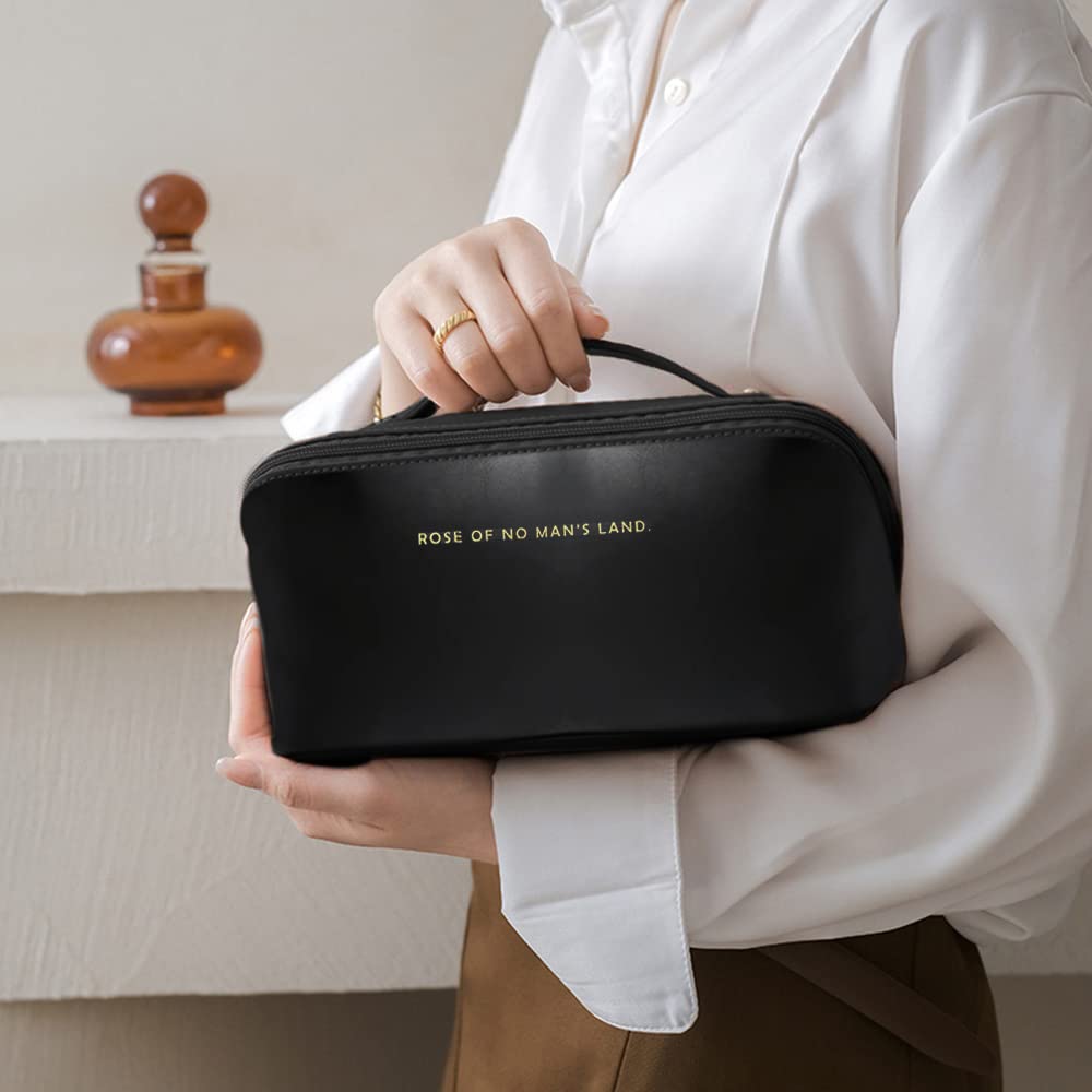 Black cosmetic bag held by hand with top handle and centered logo text