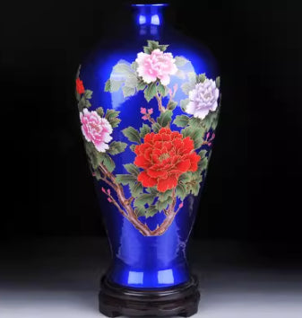 Ceramic vase in blue with multicolor blossom pattern and glossy base.