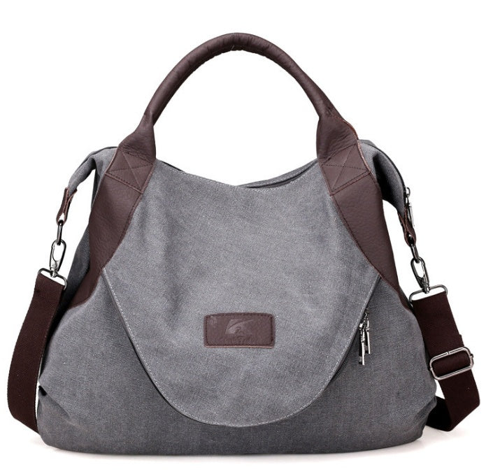 Gray canvas shoulder crossbody bag with dark brown handles, side zippers, and strap