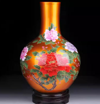 Orange ceramic vase with green leaves and pink-red floral design, glossy base.
