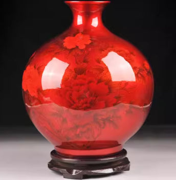 Glazed red ceramic vase with central flower motif and dark base.