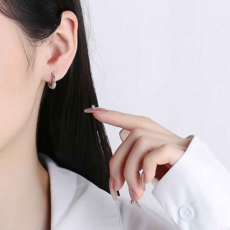 Sterling silver hoop earrings with oval zircon sparkle, worn by model on ear