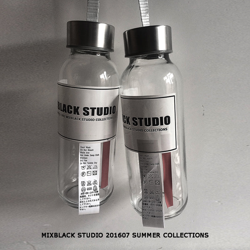Front view of two clear glass water bottles with black screw caps