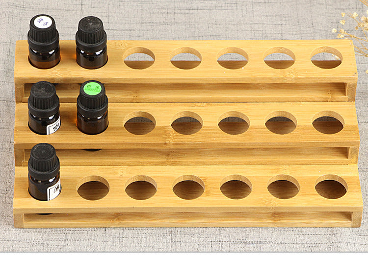 Wood essential oil bottle rack with multiple round holes and several dark bottles