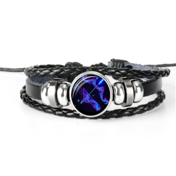 Braided leather-look bracelet with round glowing zodiac pendant and silver-toned hinged links.
