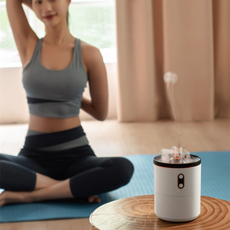 Aroma diffuser humidifier, white cylinder with orange glow beside a yoga mat
