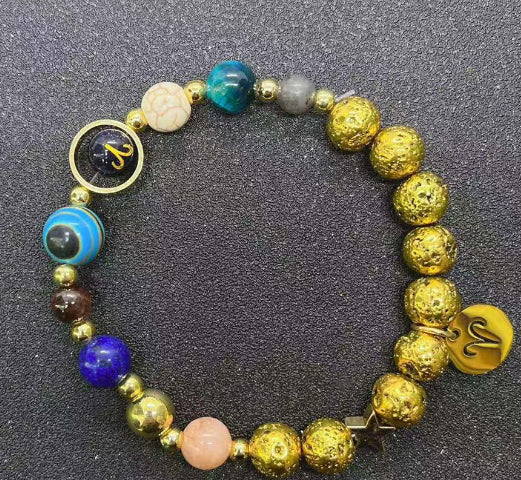 Gold beaded bracelet with teal and blue stones, gold heart charm, and zodiac disc charms