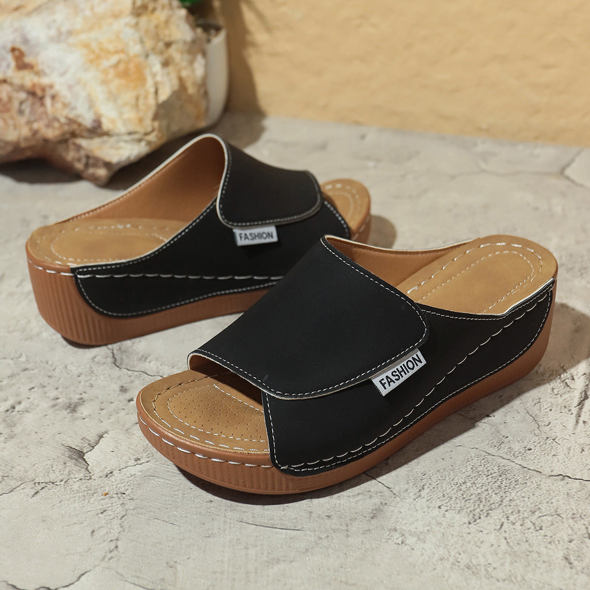Women’s black wedge slides with open toe, decorative stitching, and brown platform sole