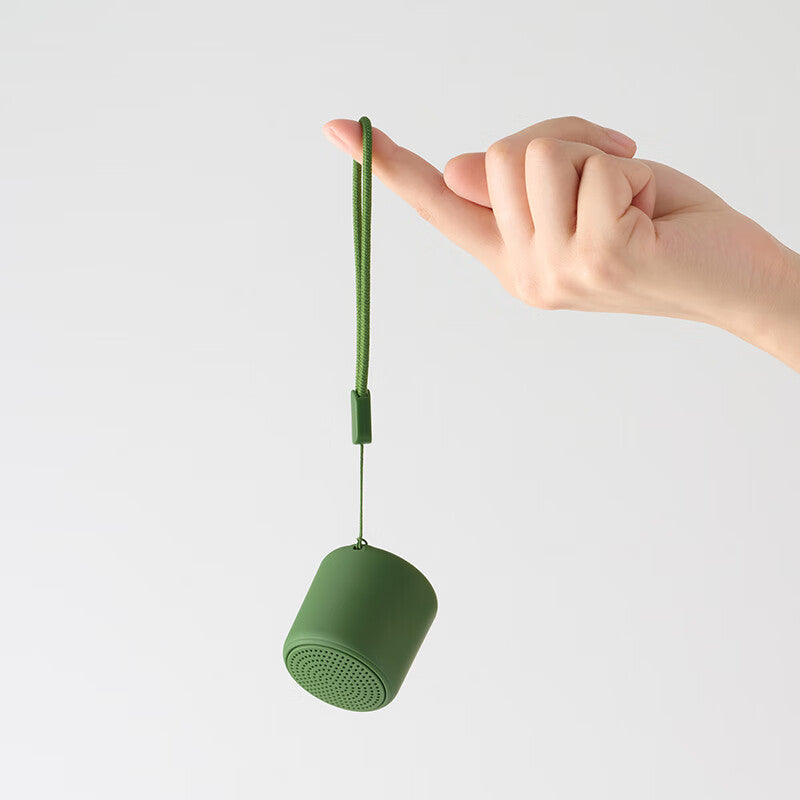 Portable wireless mini speaker, green cylindrical body with perforated top and cord loop