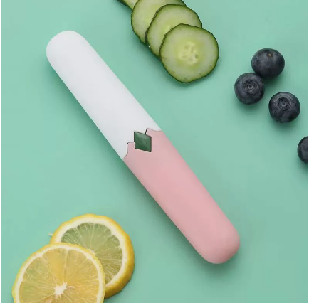 Two-in-one fruit knife with white handle and pink sleeve, green blade insert, on surface