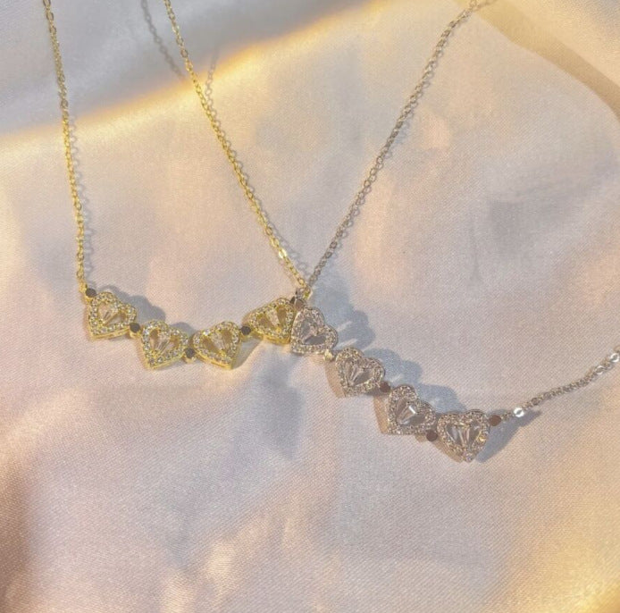 Gold-tone clover pendant necklace with multiple heart-like crystal charms on chain