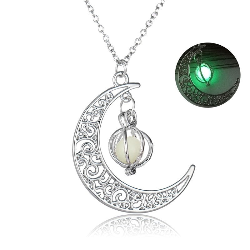 Silver crescent moon charm necklace with glowing green stone on a chain