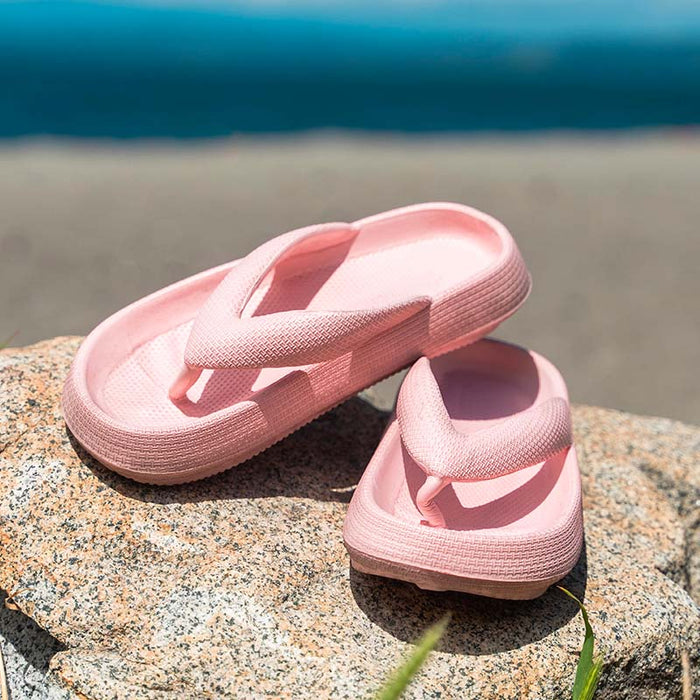 Pink thick-bottom flip flops with wide straps in a pair