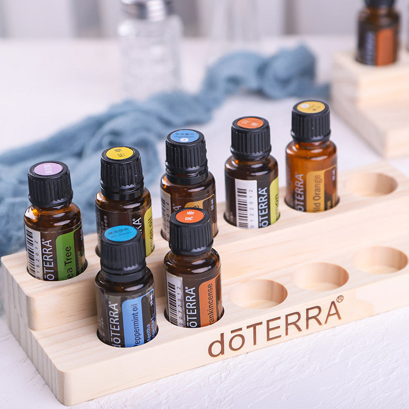 Essential oil display stand holding aromatherapy bottles in slots, light wood, dōTERRA logo
