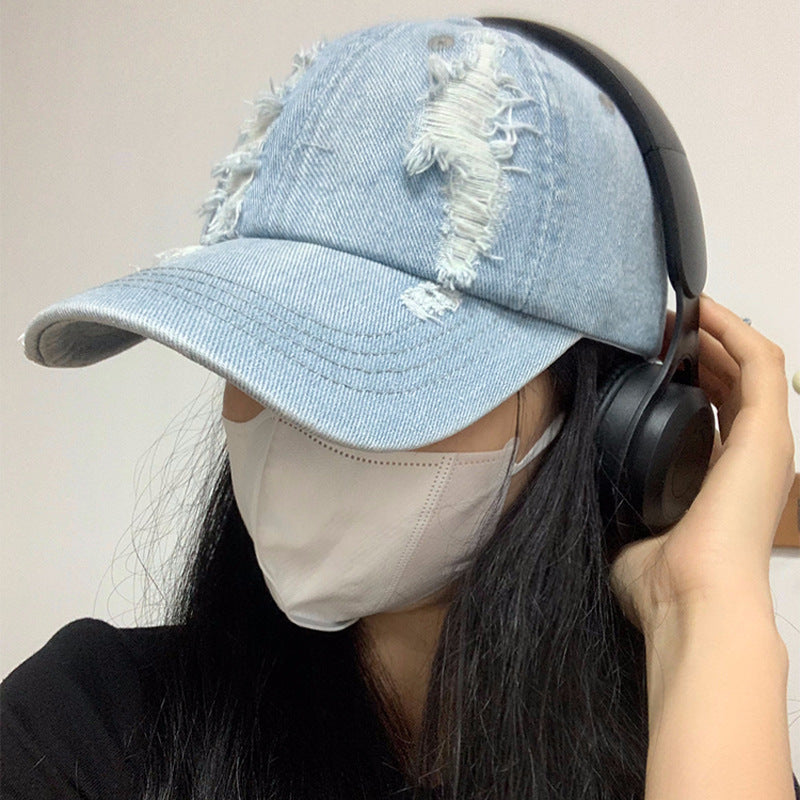 Light blue denim baseball cap with large ripped patches on the front
