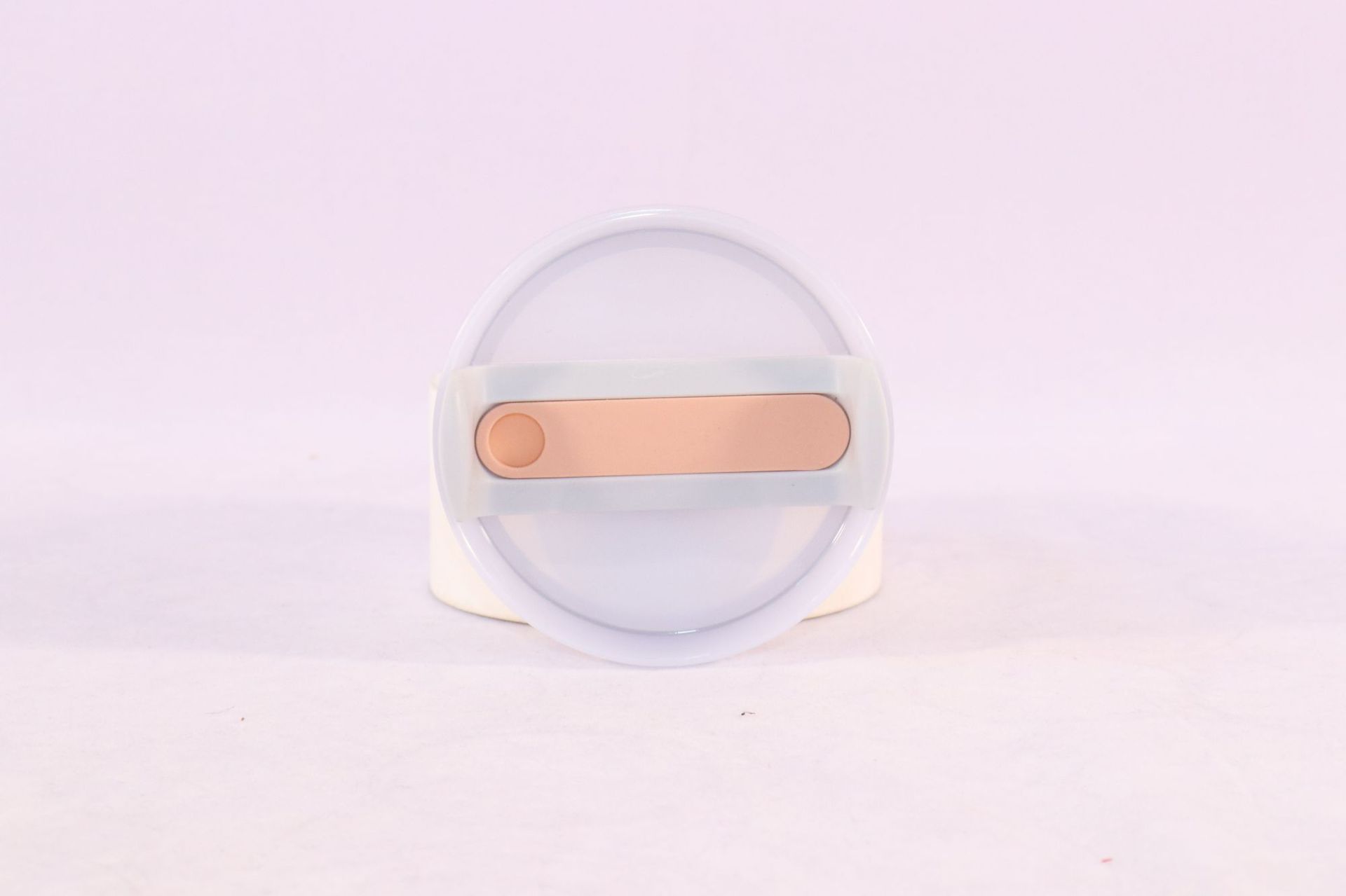 Tumbler lid with straw opening and peach slider, translucent top disc.