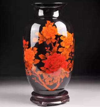 Ceramic vase with orange-red blossoms on light body, dark foot pedestal base
