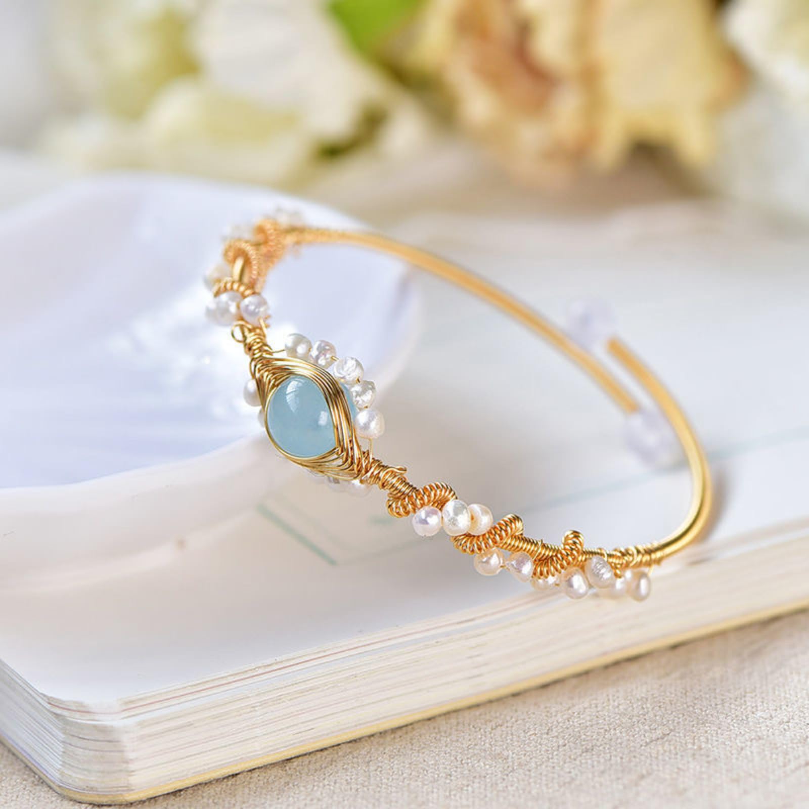 Gold pearl cuff bracelet with braided knots, blue oval center and white pearls