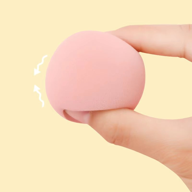 Pink teardrop makeup sponge held in a hand