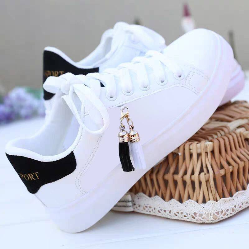 White sneakers with black heel trim and tassel charm, lace-up.