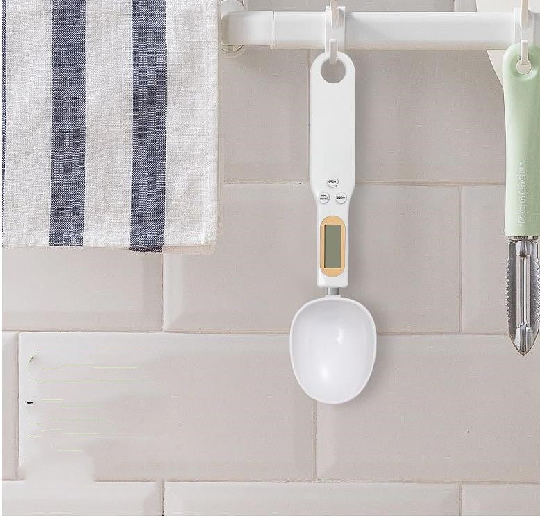 White hanging measuring spoon scale with round spoon and LCD screen.