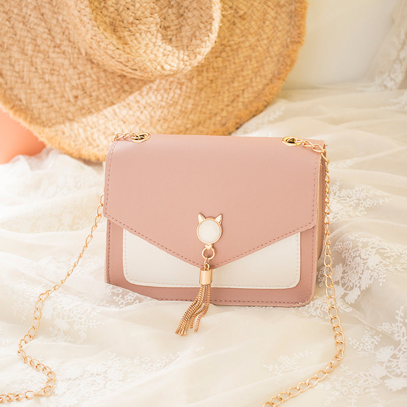 Blush pink small messenger bag with cat charm, tassel drop, and gold chain strap