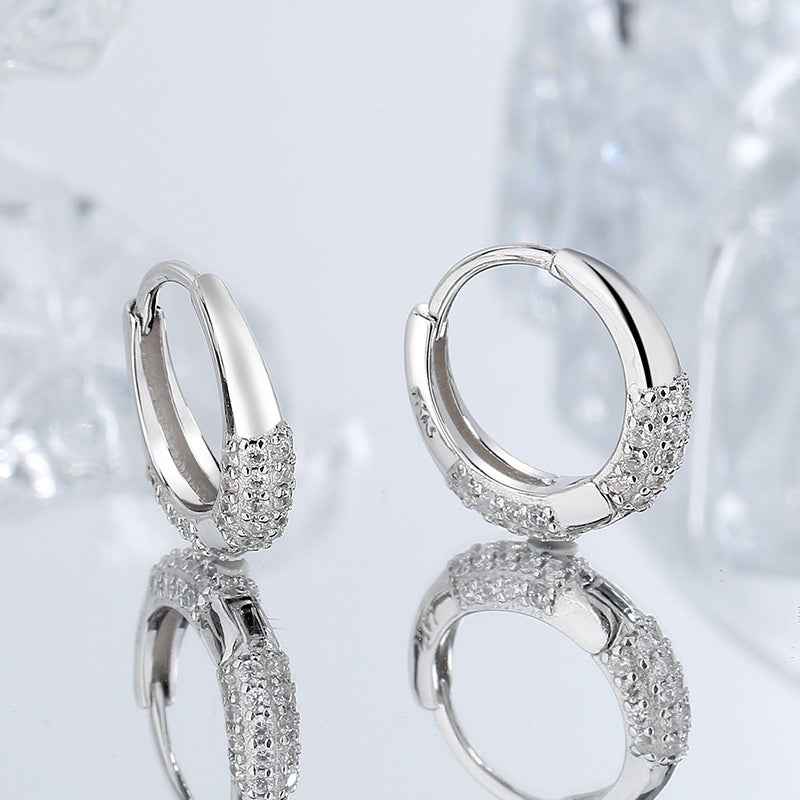 Sterling silver oval hoop earrings with textured zircon band detail, close-up pair