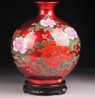 Red ceramic vase with green foliage and pink-and-white blossom pattern, base.
