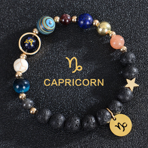 Zodiac bracelet with black lava beads and Capricorn charm, gold-tone disc charm.