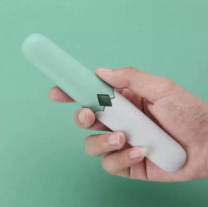 Two-in-one fruit knife held in hand, white handle with pink sleeve and green blade insert