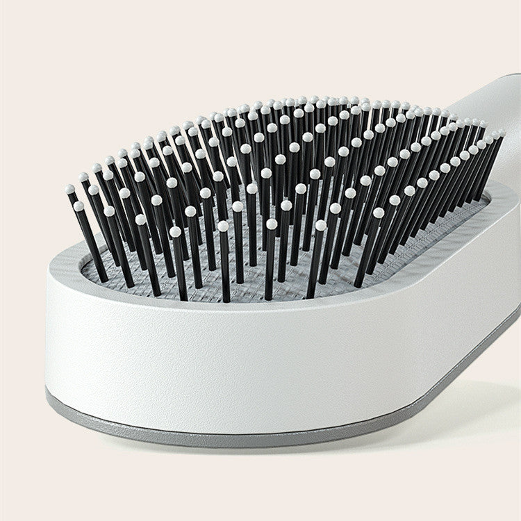 Self-cleaning hair brush cleaning base with upright black pins and white tips