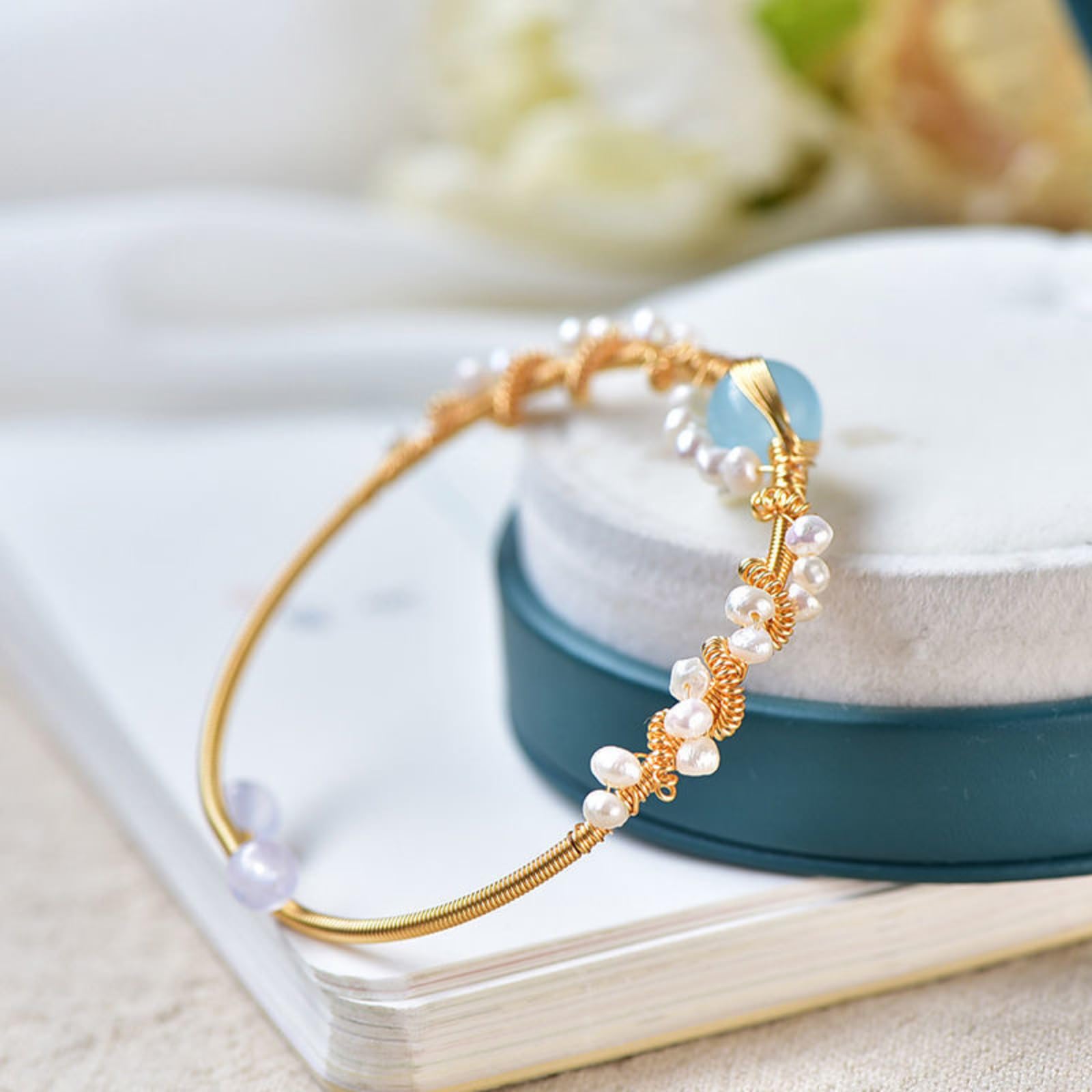 Gold pearl cuff bracelet with blue oval charm and dangling white bead accents